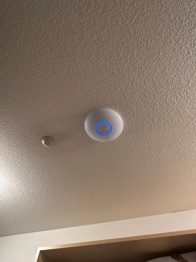 Ceiling-mounted wireless access point with its status light on after installation