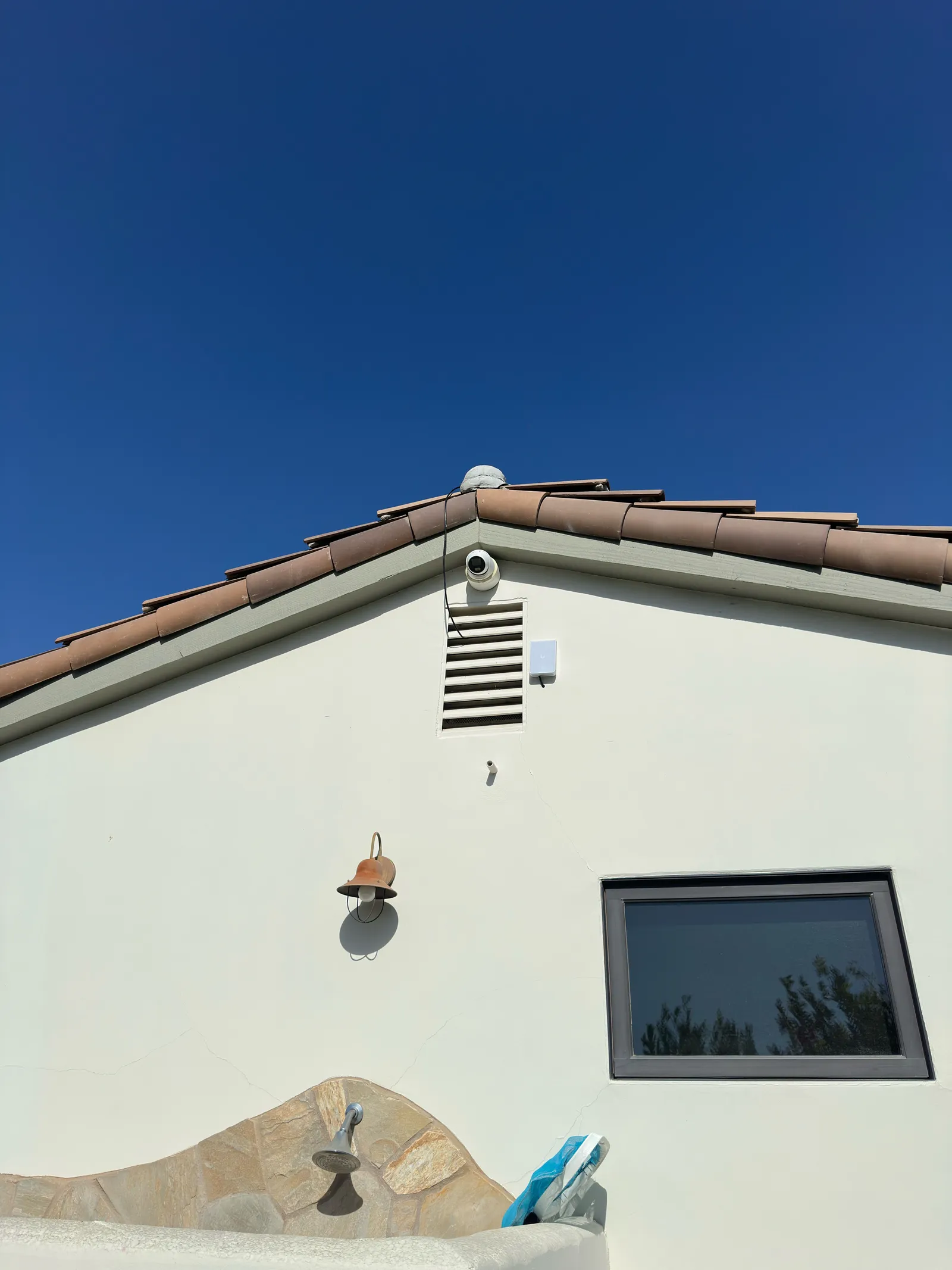 Dome security camera wired in under the roof eave of a stucco home in Orange County