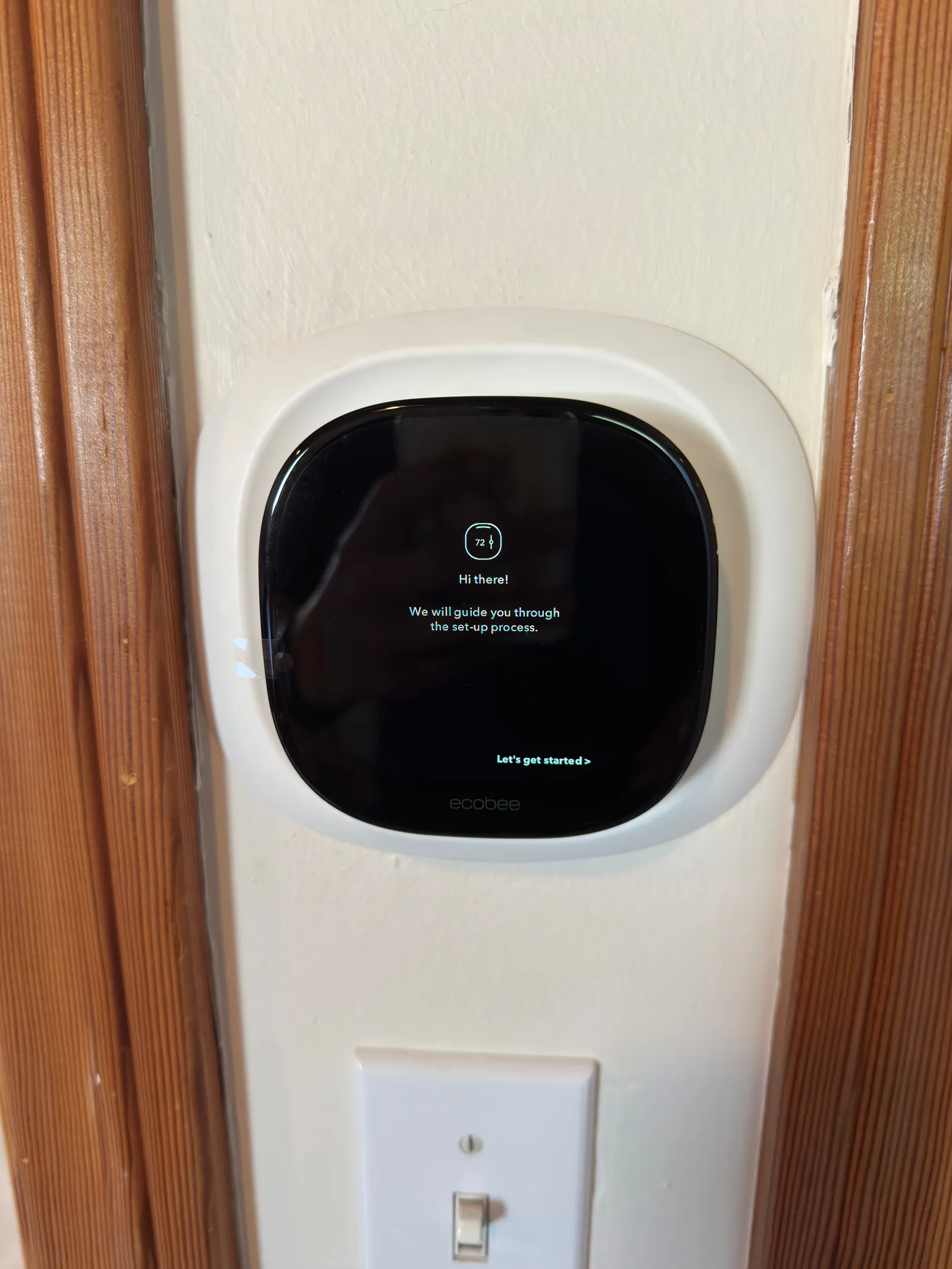 Smart thermostat on a home wall showing its guided setup screen after installation