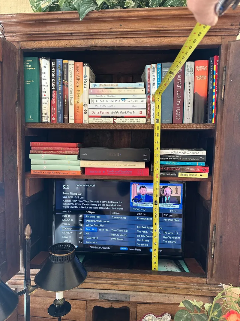 Measuring a cabinet opening with a tape measure before fitting a new television